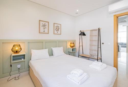 a bedroom with a white bed with towels on it at Marina Sol by Atlantic Places in Albufeira