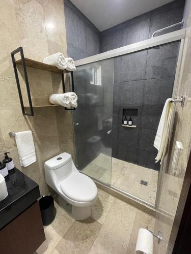 a bathroom with a toilet and a glass shower at Risco Centro de Bucerías beachfront with pool in Bucerías