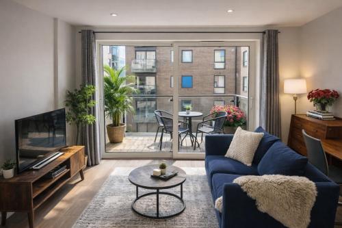 a living room with a blue couch and a large window at FruitTrees Serviced Apartment in Cambridge