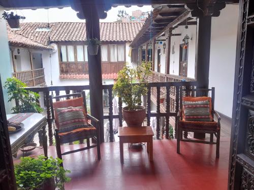 un balcone con sedie, un tavolo e una pianta in vaso di Puma walkers a Cuzco