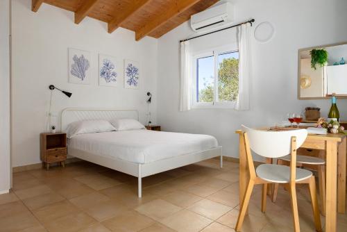 a white bedroom with a bed and a desk at Casa Garrover - Calma entre Sabinas in Illes Balears