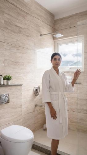 a woman in a white robe standing in a bathroom at Hotel Chail Residency in Chail
