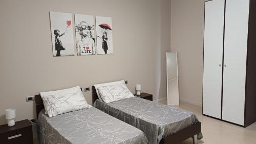 a bedroom with two beds and a picture on the wall at La Maison du Coeur in Bari