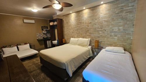 a bedroom with two beds and a brick wall at Villa Ayê Socorro SP - Pousada Petfriendly in Socorro