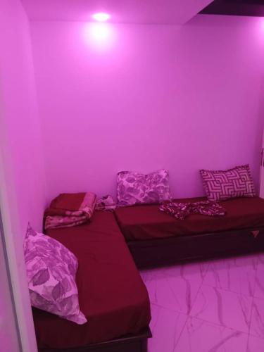 two beds in a room with purple lighting at Appartement Saket Plage in Taranimt