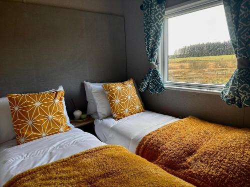 a small room with two beds and a window at Barnharrow Holiday Park in Newton Stewart