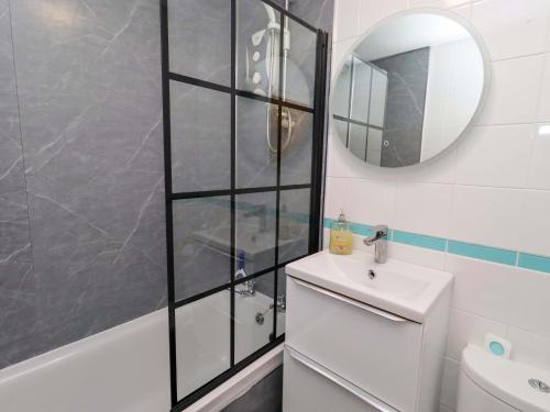 a bathroom with a shower and a sink and a mirror at Sunrise Cottage in Chathill