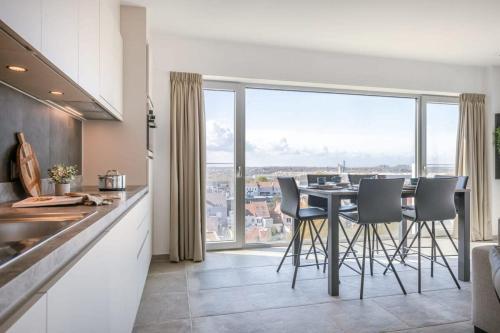 a kitchen with a table with chairs and a large window at Casiola - Bright apartment with seaview in Bredene