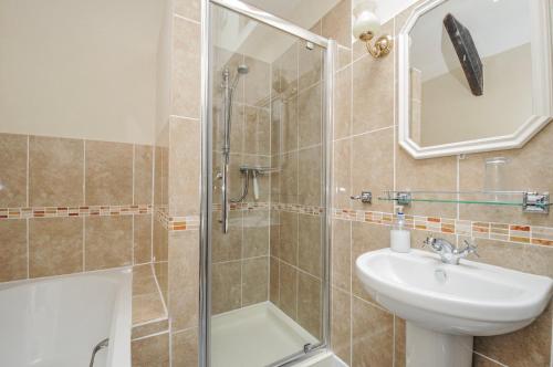 a bathroom with a shower and a sink and a mirror at Tumrose Cottage in Blisland