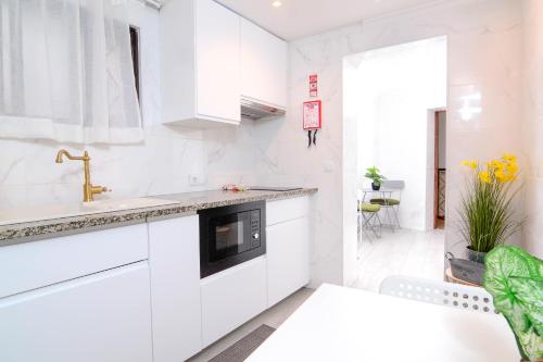 a white kitchen with white cabinets and a sink at Live Oporto Rooms in Porto
