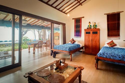 a living room with two beds and a table at Villa Kampung Kecil Beach Front in Kubu