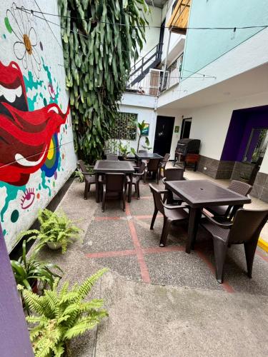 a patio with tables and chairs and a wall with plants at Rock Hostel Medellin in Medellín