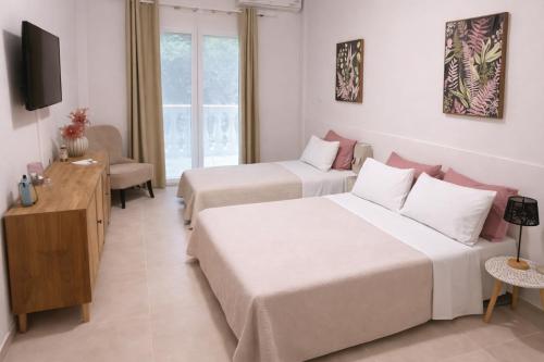 a hotel room with two beds and a television at Terranova beach apartment -Rose in Ipsos