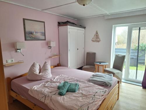 a bedroom with a bed with two green towels on it at Pension zum Meer in Breege