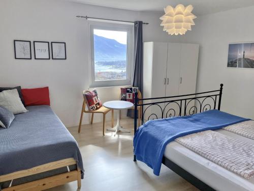 a bedroom with two beds and a table and a window at La Margaritta by Fewotessin in Minusio