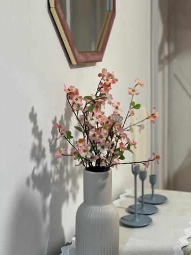 a white vase with pink flowers in it on a table at Zozy Gladstone in London