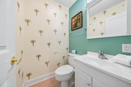 a bathroom with a white toilet and palm trees wallpaper at 803 Clipper Court in Hilton Head Island