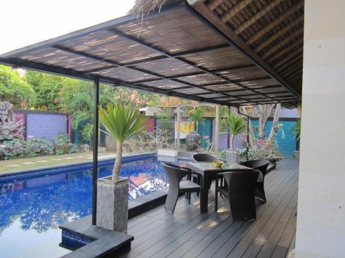 a patio with a table and chairs next to a swimming pool at Bamboo Moon Villas in Sanur