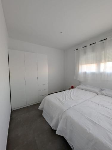 a white bedroom with a bed and a window at Casa Diego in Alcañiz