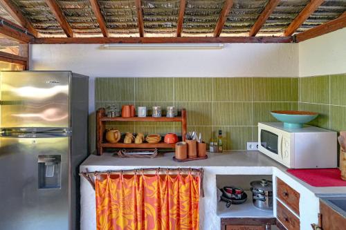 a kitchen with a refrigerator and a microwave at Charming 1BR Garden Bungalow in Temae