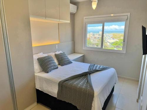 a small bedroom with a bed and a window at Apartamento com vista mar e perto da praia in Tramandaí