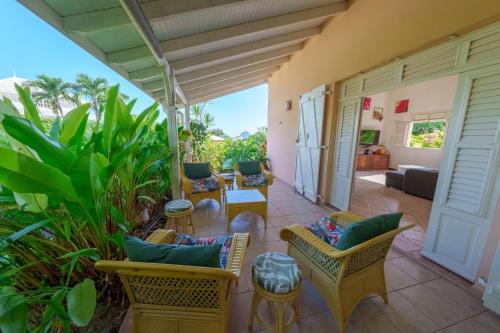 a patio with chairs and tables and a couch at Villa Providencia jacuzzi 1 min plage Le Diamant in Le Diamant