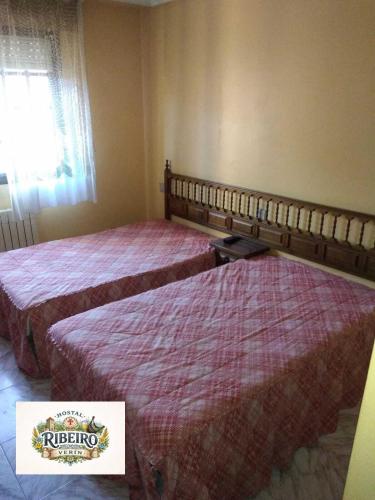 two beds in a hotel room with a sign on it at Hostal Ribeiro Verín in Verín