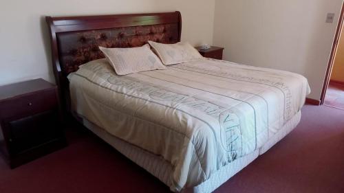 a bedroom with a large bed with a wooden headboard at Chalet yuris in Melipilla