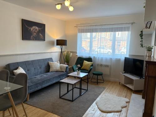 a living room with a couch and a tv at Modern apartment in Glasgow West End, free parking in Scotstoun West Station
