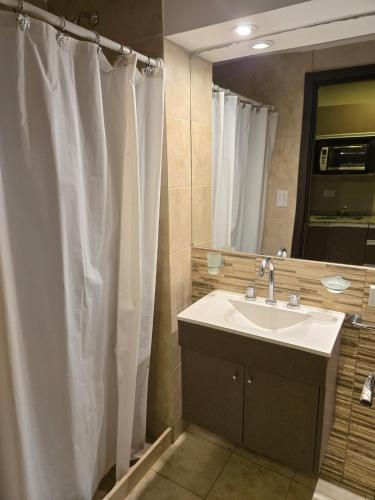 a bathroom with a sink and a shower curtain at Casa del Parque estudio 4 pax in Necochea