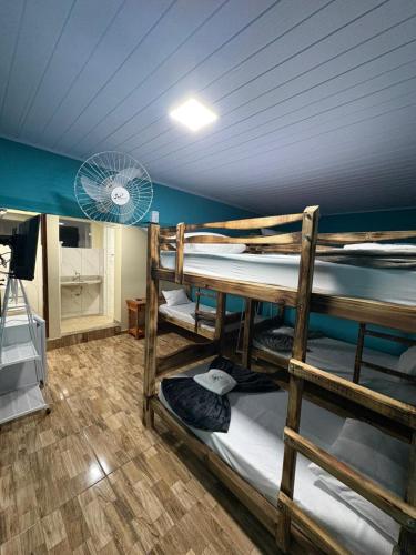 a room with three bunk beds in a room with a fan at Pousada JV Para-tí in Paraty