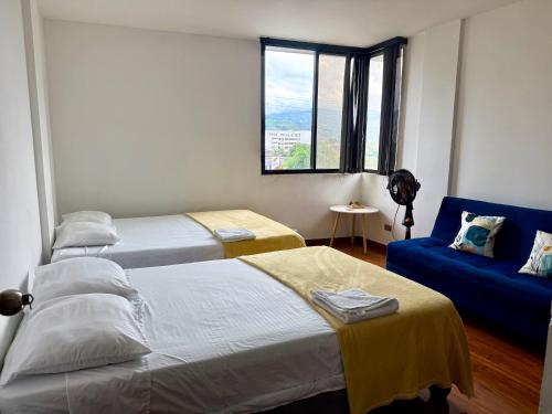a bedroom with two beds and a blue couch at Tequendama Amplio apto Cerca a clínicas in Cali