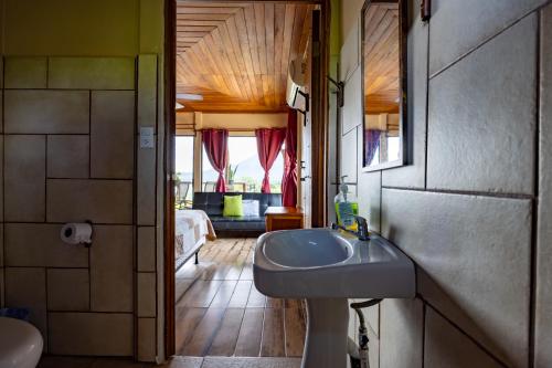 a bathroom with a sink and a mirror and a bedroom at Lua Pele House - Arenal Volcano & Lake views in El Castillo de La Fortuna