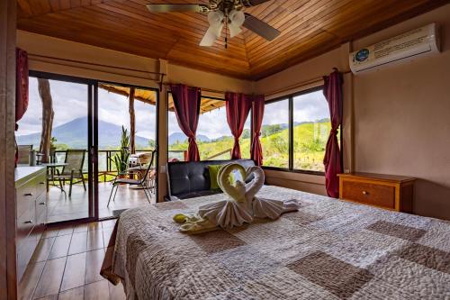 a bedroom with a bed with a large window at Lua Pele House - Arenal Volcano & Lake views in El Castillo de La Fortuna