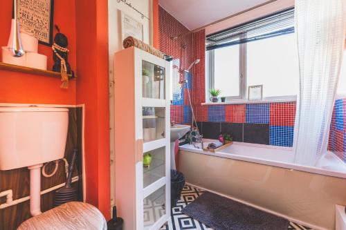 a bathroom with orange walls and a tub and a sink at The Serene Residence with Hot Tub, Sauna and Cinema Experience in London
