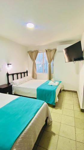 ein Hotelzimmer mit zwei Betten und einem Flachbildfernseher in der Unterkunft Hotel S Barbara in Mazatlán