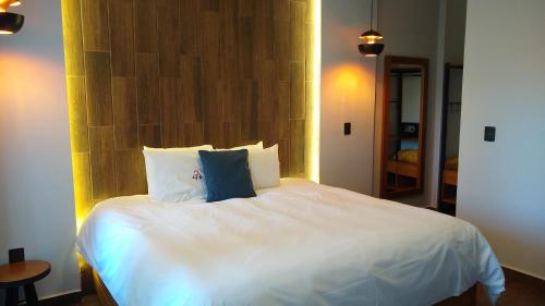 a bedroom with a large white bed with blue pillows at HOTEL REAL DEL MONTE WOODs in Mineral del Monte