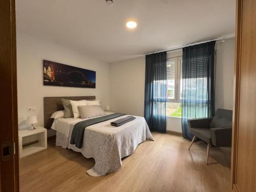 a bedroom with a bed and a chair and a window at LUGO Stay in Lugo