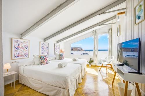 two beds in a room with a large window at Labreña Hotel in Los Caños de Meca
