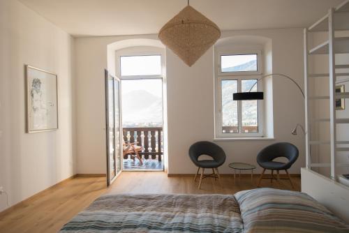 メラーノにあるFürstensteinのベッドルーム1室(椅子2脚、ベッド1台付)、バルコニーが備わります。