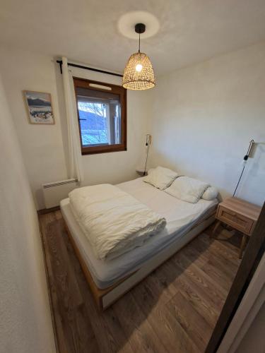 a bedroom with a white bed and a window at Entre lac et montagne in Les Angles