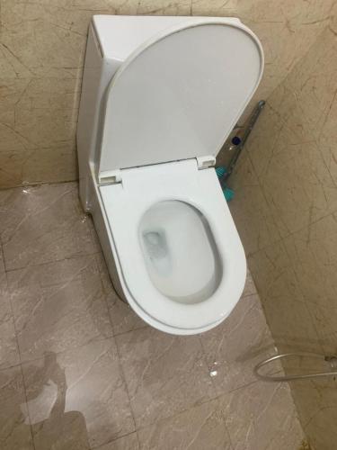 a white toilet in a bathroom with its seat up at The Moksha Residency in Prayagraj