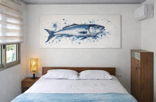 a bedroom with a bed with a fish painting on the wall at Aquitania in Rincón