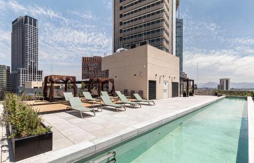 a pool on the roof of a building with chairs at Kukun Reforma & Downtown in Mexico City