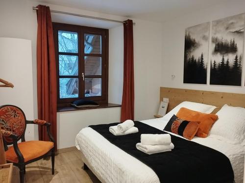 a bedroom with a bed and a chair and a window at O Clarée in Val-des-Prés