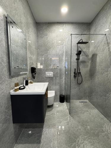 a bathroom with a sink and a shower and a toilet at Sorelle Hotel in Prizren