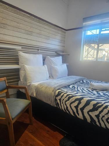 a bedroom with a bed and a chair and a window at Ludinz Self Catering Accommodation Bellville in Avondale