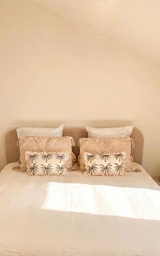 a bed with four pillows on top of it at Oasis proche du Futuroscope in Saint-Cyr