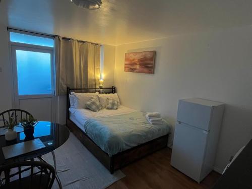 a small bedroom with a bed and a table and a refrigerator at Studio near Addenbrookes and Centre By Miller Residence in Cherry Hinton