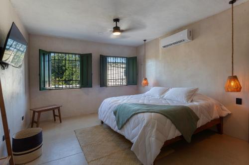 a bedroom with a large bed and two windows at Casa Calma 45 in Mérida